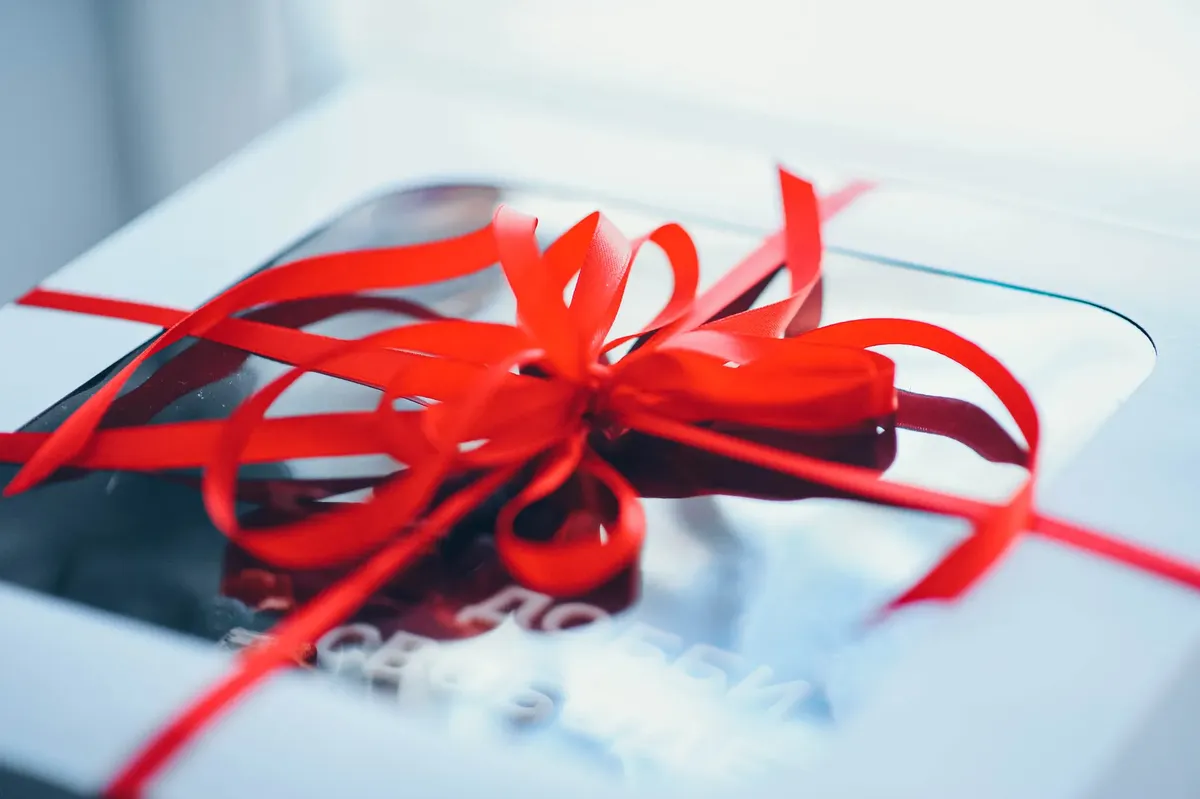 A close-up shot of a sophisticated gift box wrapped with a striking red ribbon bow, perfect for holiday gifting.